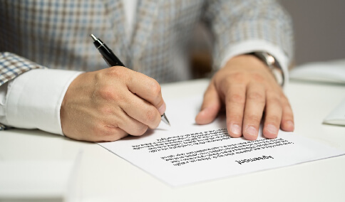 A person signing a translated agreement copy.