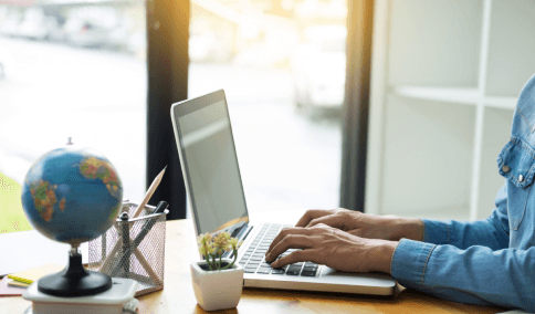 Hand typing on a laptop, representing expert translation services for birth certificates worldwide for various requirements.