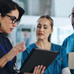 Medical team, tablet and meeting in clinic for advice, innovation and feedback with patient report. Hospital CEO, people or tech in lobby with results, solution or professional opinion for healthcare.